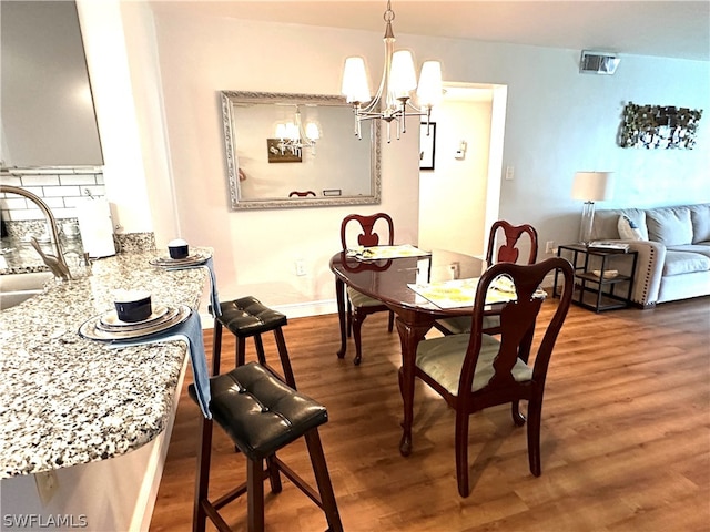 dining room with a notable chandelier, sink, and dark wood-type flooring