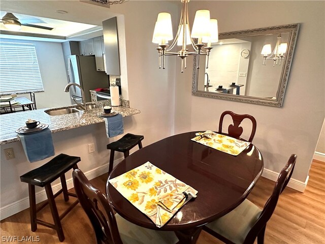 dining room with light wood-type flooring, sink, and an inviting chandelier