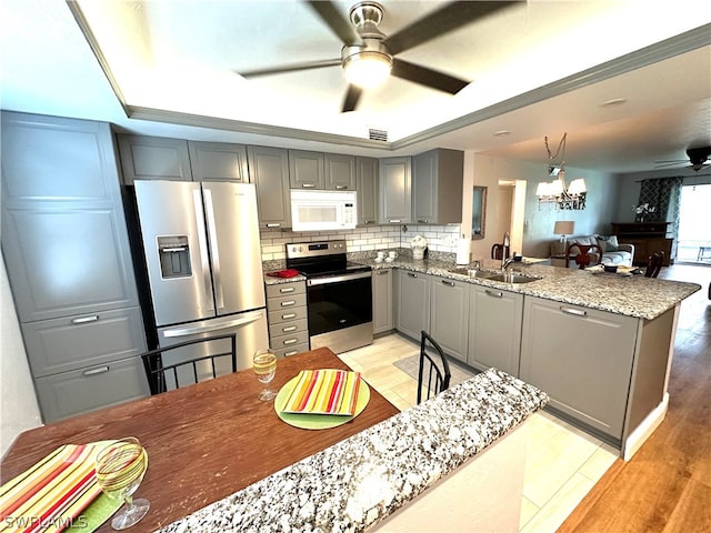 kitchen featuring ceiling fan with notable chandelier, light hardwood / wood-style flooring, stainless steel appliances, and sink