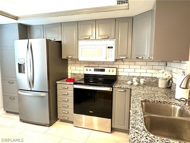 kitchen featuring a sink, appliances with stainless steel finishes, gray cabinets, and tasteful backsplash