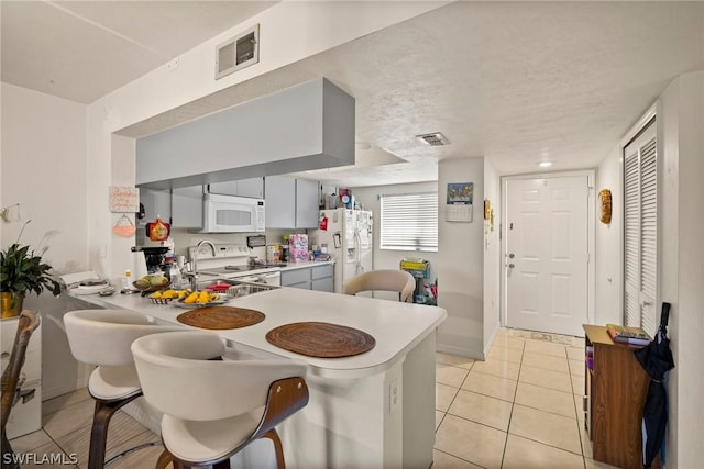 kitchen featuring white appliances, light tile patterned floors, and a textured ceiling