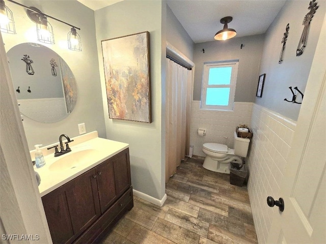 bathroom featuring hardwood / wood-style floors, tile walls, toilet, and vanity