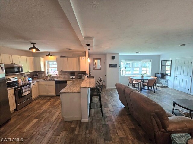 kitchen with a breakfast bar, sink, white cabinetry, kitchen peninsula, and stainless steel appliances