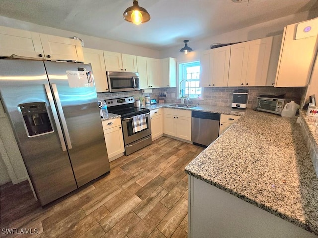 kitchen featuring appliances with stainless steel finishes, sink, white cabinets, decorative backsplash, and light stone counters