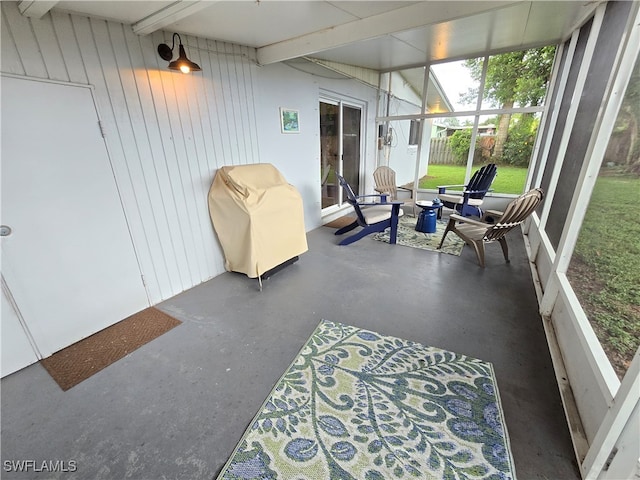 sunroom / solarium featuring vaulted ceiling with beams