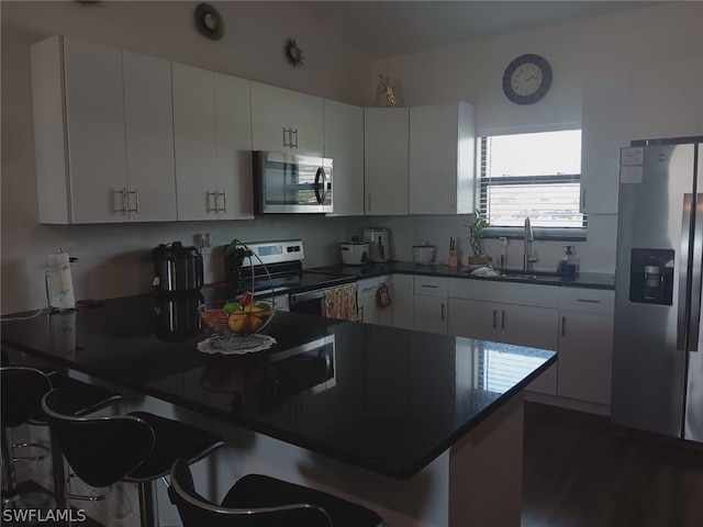 kitchen with white cabinetry, kitchen peninsula, stainless steel appliances, a kitchen breakfast bar, and sink