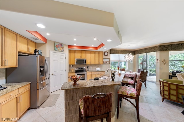 kitchen with appliances with stainless steel finishes, a healthy amount of sunlight, and light stone countertops