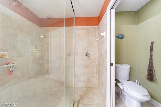 bathroom featuring tiled shower and toilet