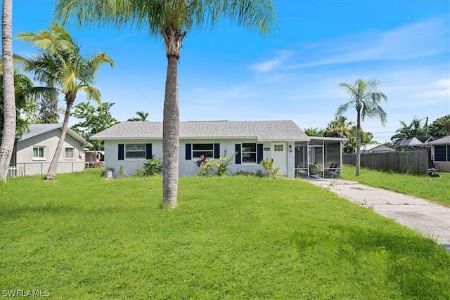 view of front facade featuring fence, a sunroom, driveway, stucco siding, and a front yard