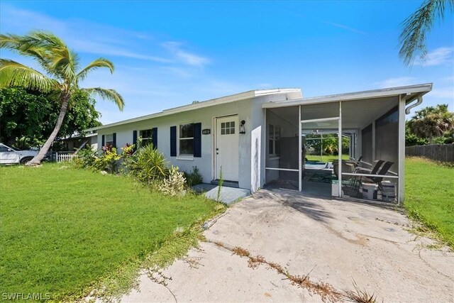 view of front of home featuring a sunroom, fence, concrete driveway, and a front yard