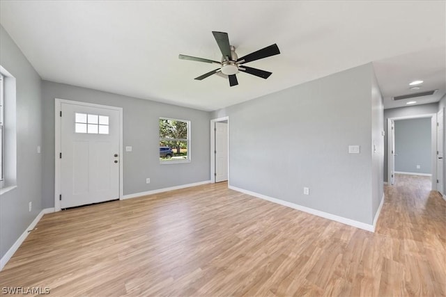 interior space featuring ceiling fan, light wood finished floors, visible vents, and baseboards