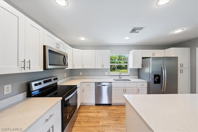 kitchen with sink, appliances with stainless steel finishes, light wood-type flooring, and white cabinets