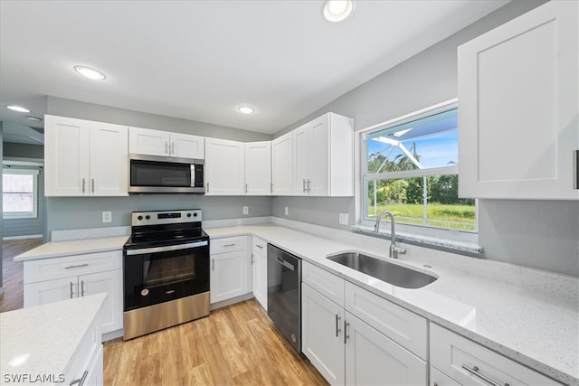 kitchen featuring white cabinets, stainless steel appliances, light hardwood / wood-style floors, and sink