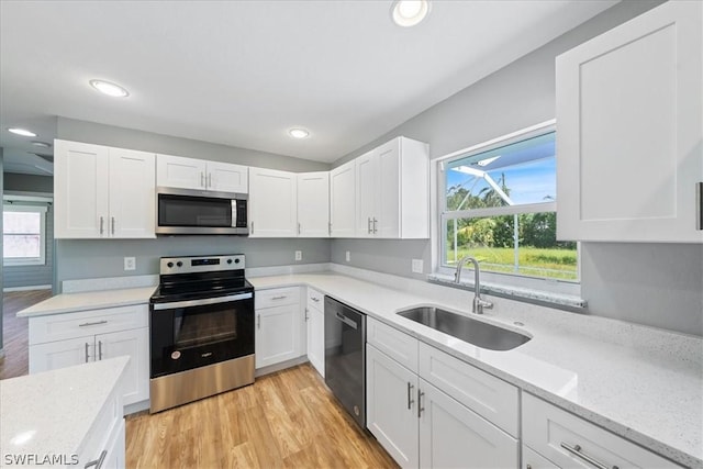 kitchen featuring recessed lighting, a sink, white cabinets, appliances with stainless steel finishes, and light wood finished floors