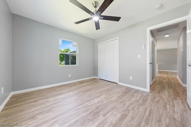 unfurnished bedroom featuring a closet, light wood-type flooring, a ceiling fan, and baseboards