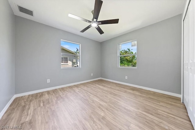 spare room featuring light wood-style floors, visible vents, baseboards, and a ceiling fan