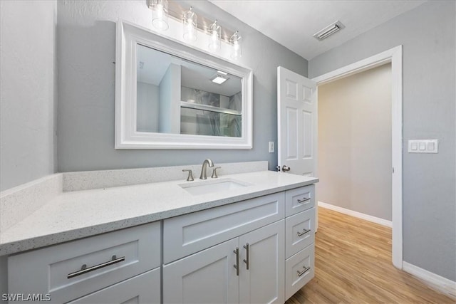 full bath with wood finished floors, vanity, visible vents, baseboards, and an enclosed shower