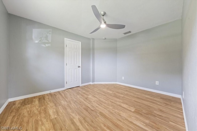 spare room with light wood finished floors, baseboards, visible vents, and a ceiling fan