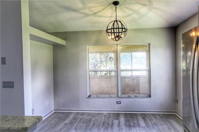 unfurnished dining area featuring a notable chandelier and wood-type flooring