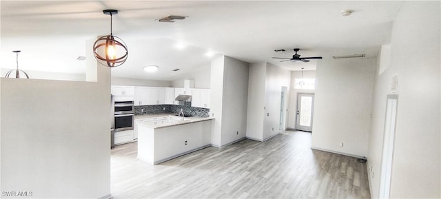 kitchen featuring stainless steel double oven, white cabinets, a towering ceiling, backsplash, and kitchen peninsula