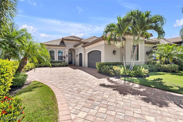 mediterranean / spanish-style home featuring a garage and a front yard