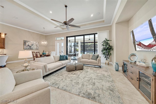 living room featuring crown molding, ceiling fan with notable chandelier, and a tray ceiling