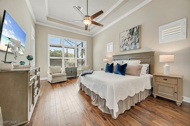 bedroom featuring ceiling fan, a tray ceiling, dark hardwood / wood-style floors, and ornamental molding