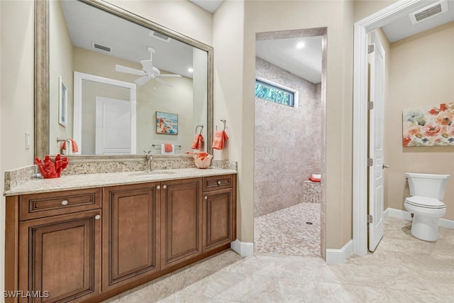 bathroom with vanity, toilet, ceiling fan, and tiled shower