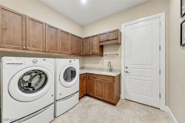 clothes washing area featuring sink, cabinets, and washer and dryer