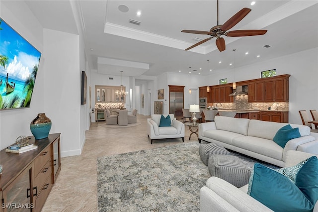 living room with visible vents, a tray ceiling, ceiling fan with notable chandelier, crown molding, and recessed lighting