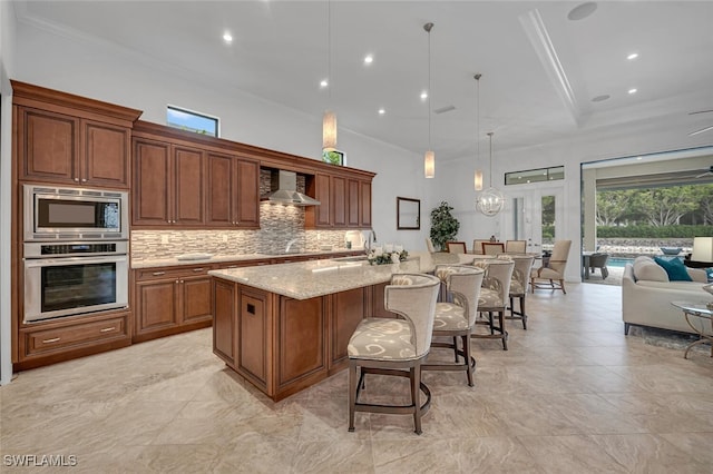 kitchen with a spacious island, wall chimney exhaust hood, appliances with stainless steel finishes, open floor plan, and pendant lighting