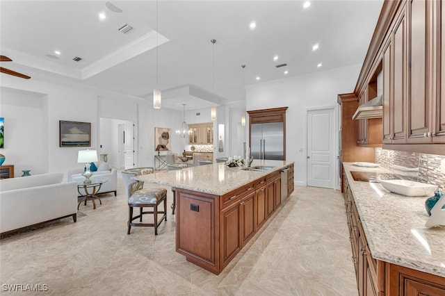 kitchen featuring light stone counters, a large island, hanging light fixtures, open floor plan, and built in refrigerator