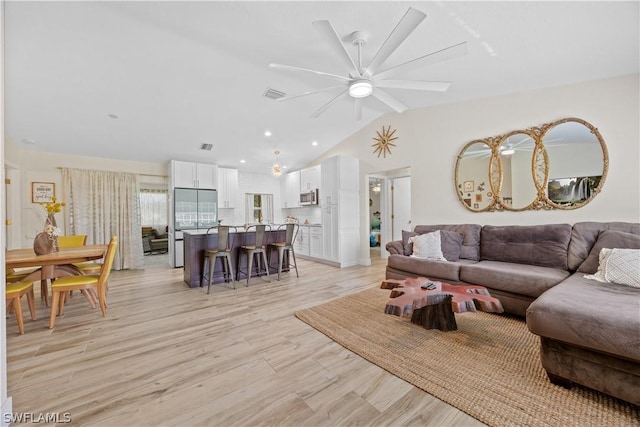 living room with ceiling fan, light wood-type flooring, and lofted ceiling