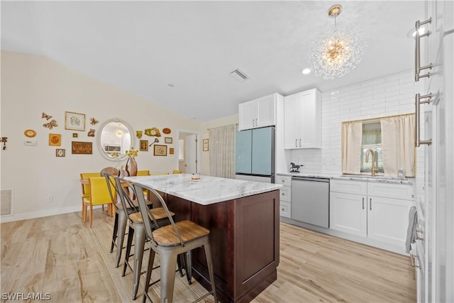 kitchen with stainless steel appliances, sink, white cabinets, a center island, and decorative backsplash