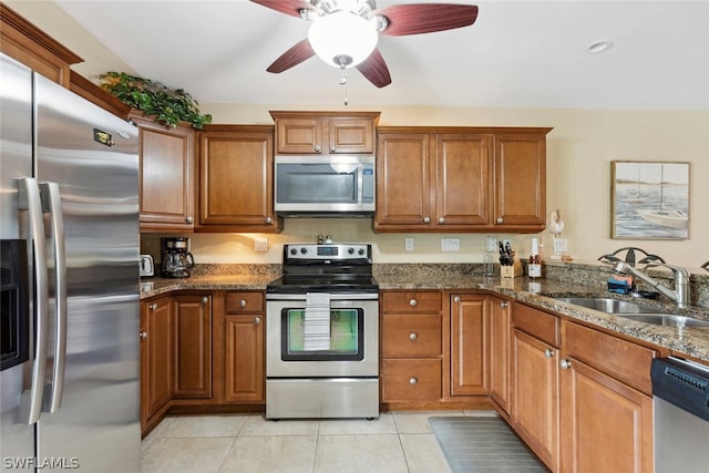 kitchen with ceiling fan, sink, light tile patterned flooring, stainless steel appliances, and dark stone counters