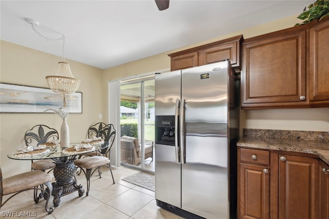 kitchen featuring decorative light fixtures, dark stone countertops, stainless steel fridge with ice dispenser, a chandelier, and light tile patterned floors