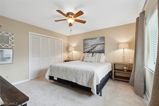 bedroom featuring ceiling fan, light colored carpet, a closet, and multiple windows