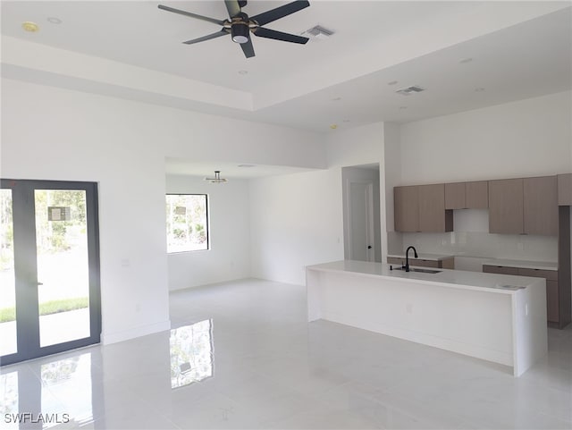 kitchen featuring light tile patterned floors, sink, ceiling fan, and an island with sink