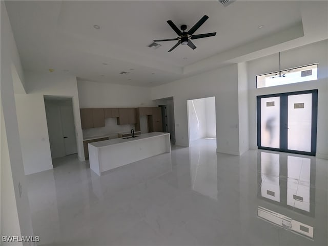 kitchen featuring a tray ceiling, ceiling fan, decorative light fixtures, and sink