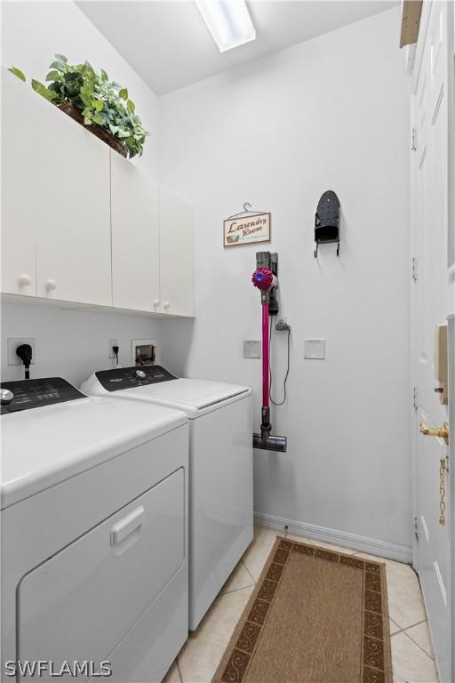 laundry area featuring light tile patterned floors, cabinets, and washer and dryer