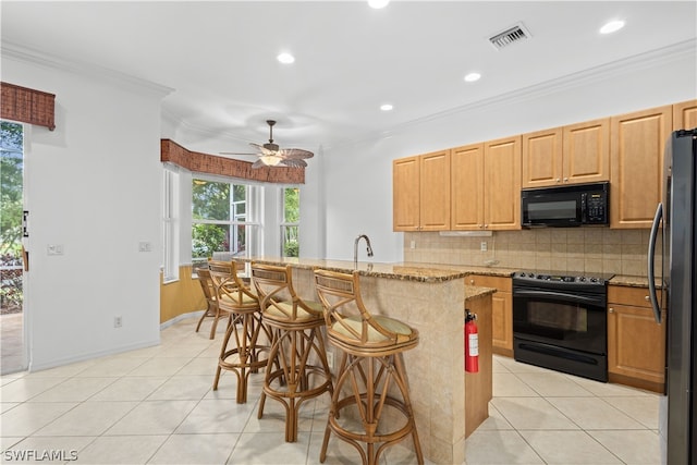 kitchen featuring ornamental molding, a kitchen bar, black appliances, light stone counters, and ceiling fan