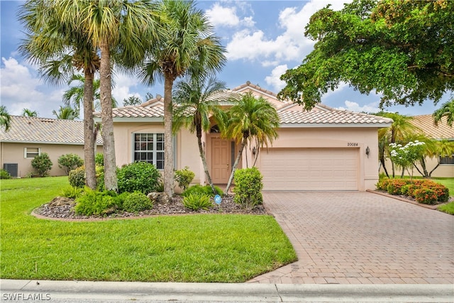 mediterranean / spanish house featuring central air condition unit, a garage, and a front lawn