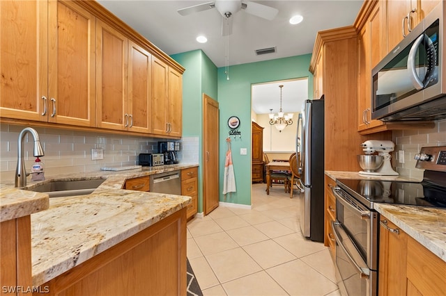 kitchen featuring backsplash, ceiling fan with notable chandelier, light stone counters, stainless steel appliances, and sink