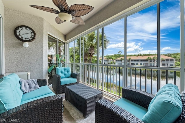 sunroom / solarium featuring a water view, plenty of natural light, and ceiling fan