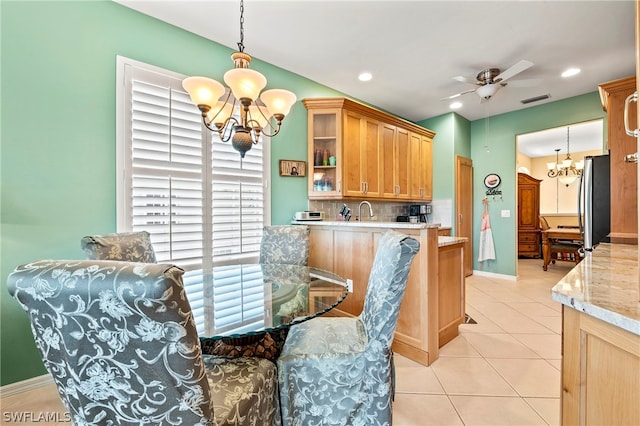 dining area featuring sink, a healthy amount of sunlight, light tile patterned floors, and ceiling fan with notable chandelier