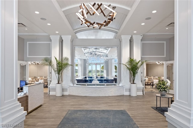 foyer entrance with an inviting chandelier, hardwood / wood-style floors, a high ceiling, and ornate columns