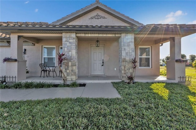 entrance to property featuring covered porch and a yard