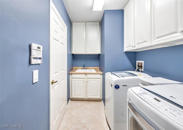 washroom with light tile patterned flooring, cabinets, sink, and washing machine and clothes dryer