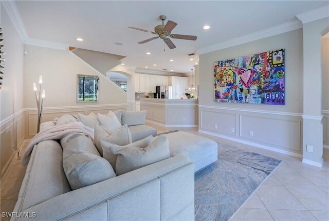 tiled living room with ceiling fan and ornamental molding