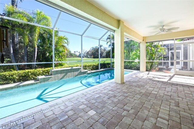 view of swimming pool featuring ceiling fan, a patio area, and glass enclosure